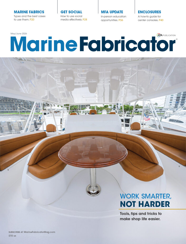 Bright white boat interior featuring a round wooden table with a polished chrome base, surrounded by tan leather seating.