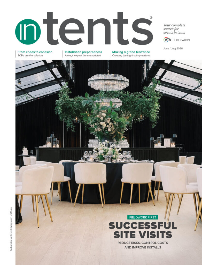 Elegant event setting with round tables, black chairs, and lush green floral arrangements under a grand chandelier, promoting site visit success.