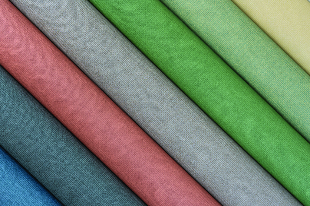 Eight folded fabric swatches in pastel shades of pink, blue, green, grey and yellow arranged diagonally, showcasing Enduratex Duet coated fabric texture and color variation.